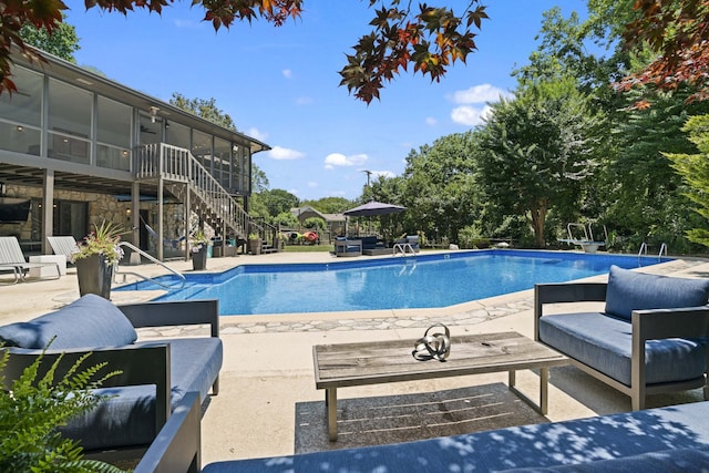 view of swimming pool with a patio and a sunroom