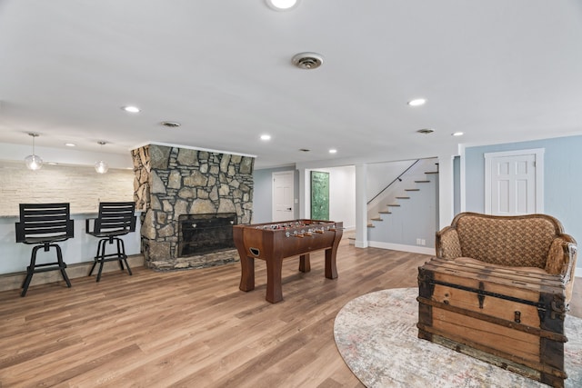 game room with light hardwood / wood-style flooring and a stone fireplace