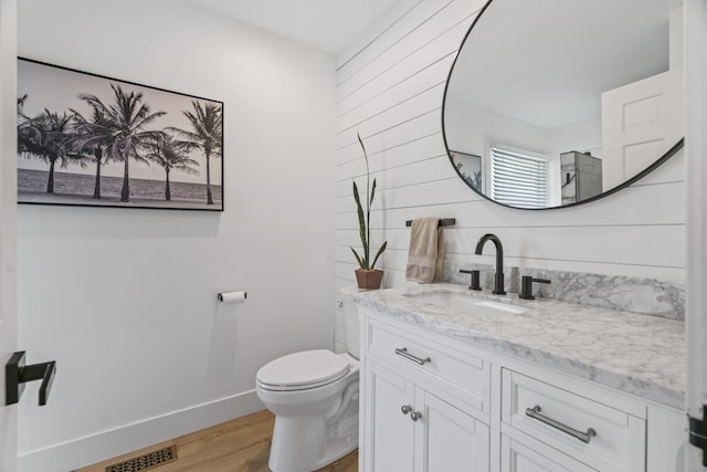 bathroom with hardwood / wood-style floors, vanity, and toilet