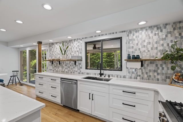 kitchen with sink, light hardwood / wood-style flooring, decorative backsplash, white cabinets, and appliances with stainless steel finishes