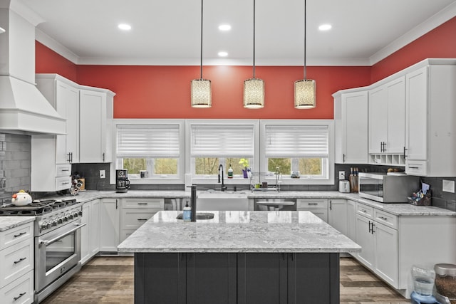 kitchen with appliances with stainless steel finishes, a kitchen island with sink, tasteful backsplash, and custom range hood