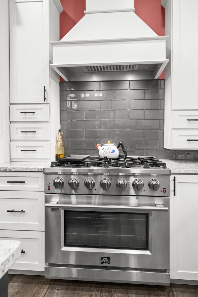 kitchen featuring light stone counters, custom range hood, tasteful backsplash, high end stainless steel range, and white cabinets