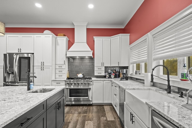 kitchen with stainless steel appliances, premium range hood, white cabinets, and tasteful backsplash