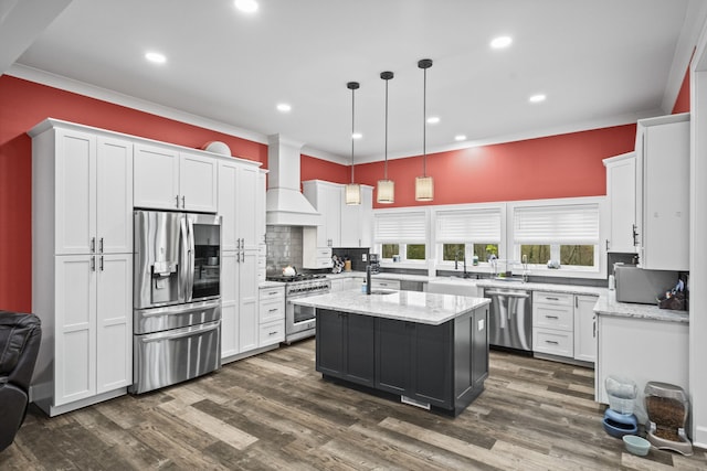 kitchen featuring custom exhaust hood, a center island with sink, appliances with stainless steel finishes, light stone countertops, and pendant lighting