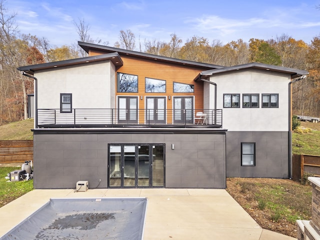 rear view of house with a balcony, a patio area, and french doors