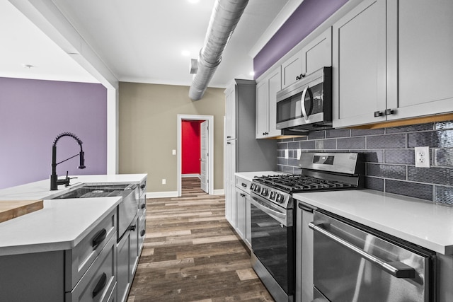 kitchen featuring sink, tasteful backsplash, dark hardwood / wood-style floors, gray cabinetry, and appliances with stainless steel finishes