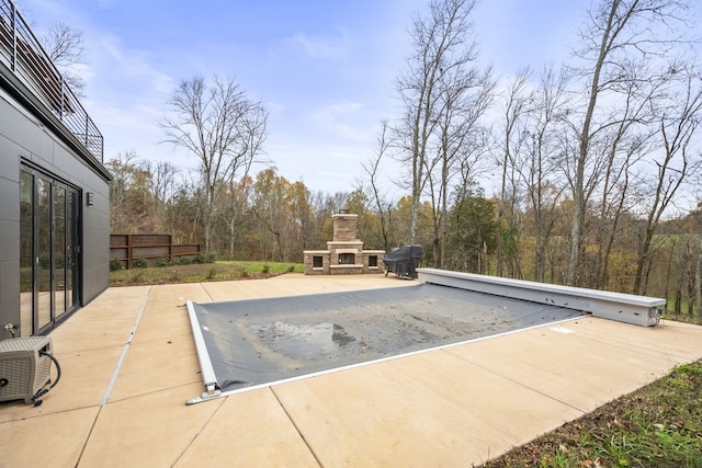 view of swimming pool with an outdoor stone fireplace and a patio