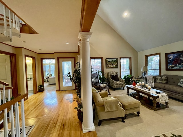 living room featuring ornate columns, light hardwood / wood-style flooring, high vaulted ceiling, and a healthy amount of sunlight