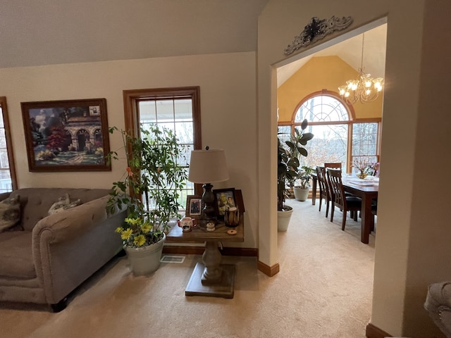 carpeted living room with vaulted ceiling and a notable chandelier