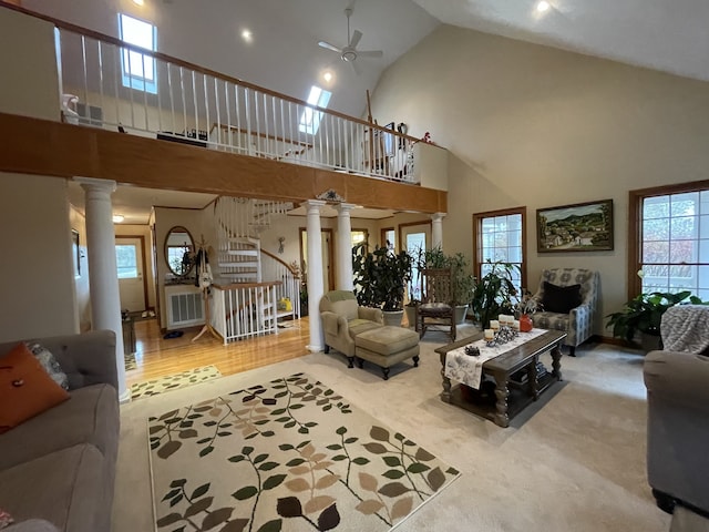 living room with hardwood / wood-style floors, ceiling fan, ornate columns, and high vaulted ceiling