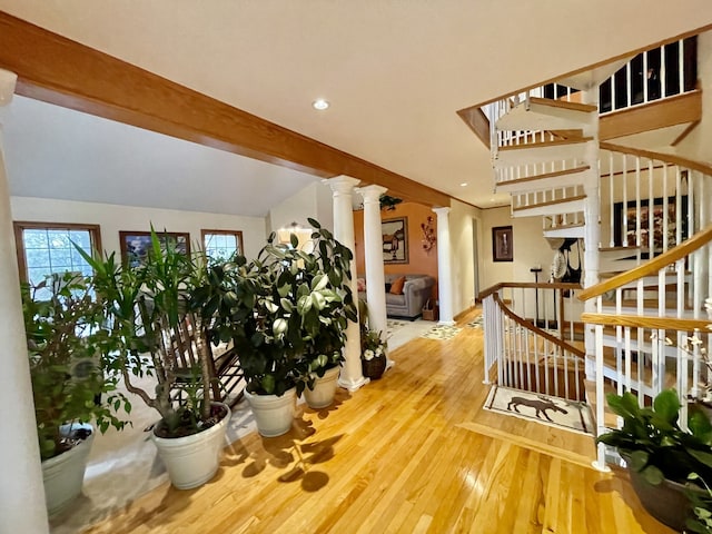 stairway featuring lofted ceiling with beams, wood-type flooring, and decorative columns