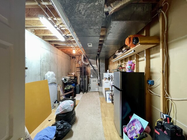 basement with stainless steel refrigerator and wood-type flooring