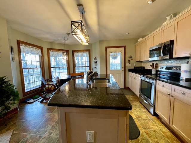 kitchen with a healthy amount of sunlight, a kitchen island with sink, sink, and appliances with stainless steel finishes