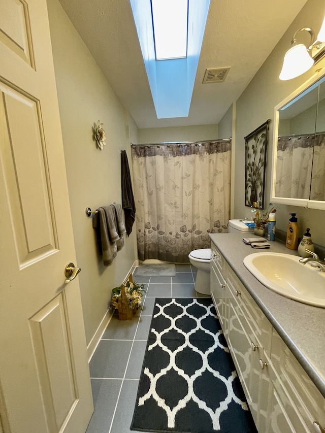 bathroom featuring a shower with shower curtain, a skylight, tile patterned floors, vanity, and toilet