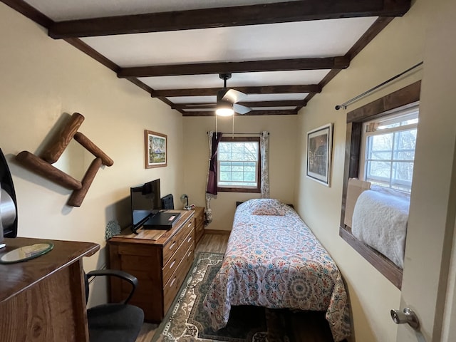 bedroom featuring ceiling fan, hardwood / wood-style floors, and beamed ceiling