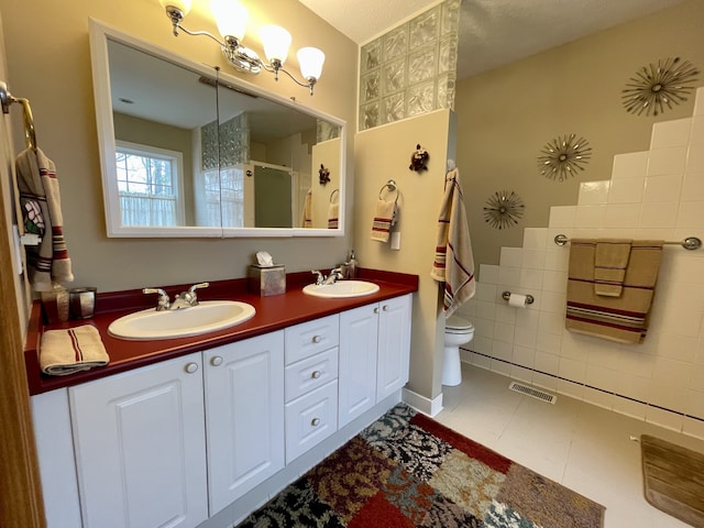 bathroom featuring tile patterned floors, a textured ceiling, toilet, vanity, and a shower with shower door