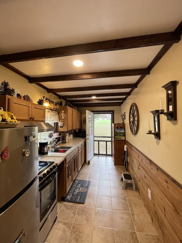 kitchen with wooden walls, sink, appliances with stainless steel finishes, and beamed ceiling