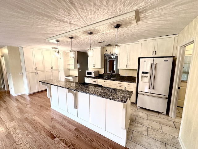 kitchen featuring decorative light fixtures, white cabinetry, stainless steel fridge with ice dispenser, and light hardwood / wood-style flooring