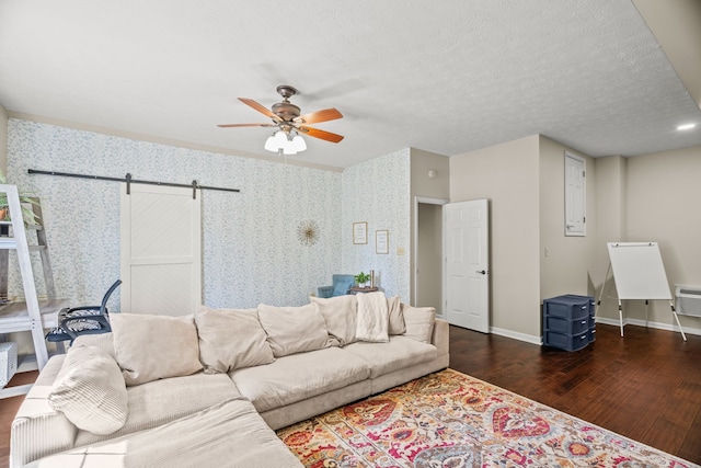 living room with a barn door, ceiling fan, and dark hardwood / wood-style floors