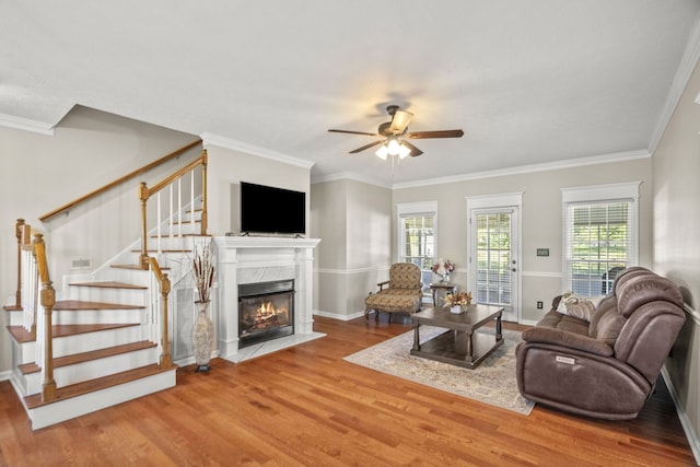 living room featuring crown molding, ceiling fan, a fireplace, and hardwood / wood-style floors