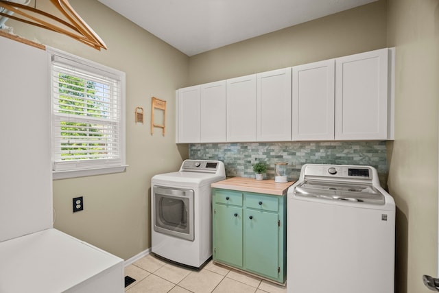 laundry area featuring baseboards, light tile patterned flooring, cabinet space, and washer and dryer