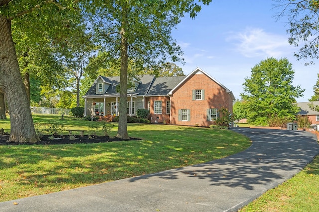 cape cod home featuring brick siding, a front yard, fence, and aphalt driveway