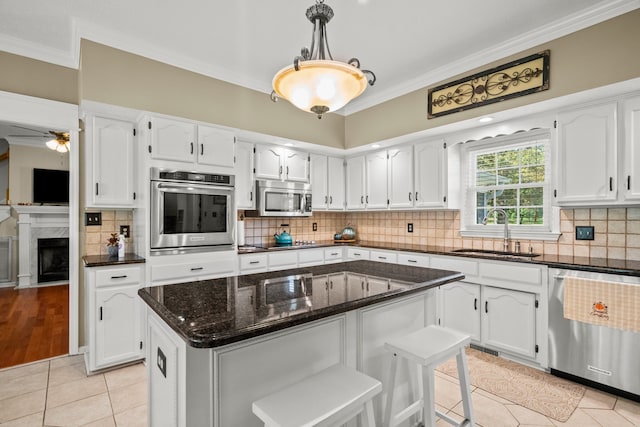 kitchen with white cabinetry, appliances with stainless steel finishes, a sink, and ornamental molding