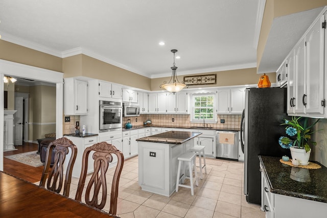 kitchen featuring appliances with stainless steel finishes, crown molding, sink, light tile patterned floors, and a kitchen island