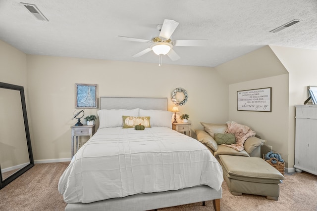 carpeted bedroom with a textured ceiling, a ceiling fan, visible vents, and baseboards