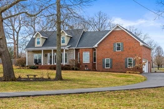 cape cod home with a garage, aphalt driveway, a front yard, and brick siding