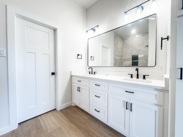 bathroom with double vanity, a sink, baseboards, and wood finished floors