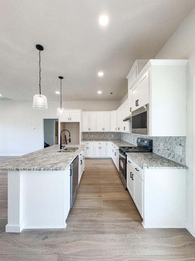 kitchen with appliances with stainless steel finishes, white cabinets, a sink, and an island with sink