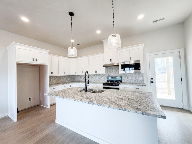 kitchen with range with gas stovetop, pendant lighting, stainless steel microwave, visible vents, and white cabinetry