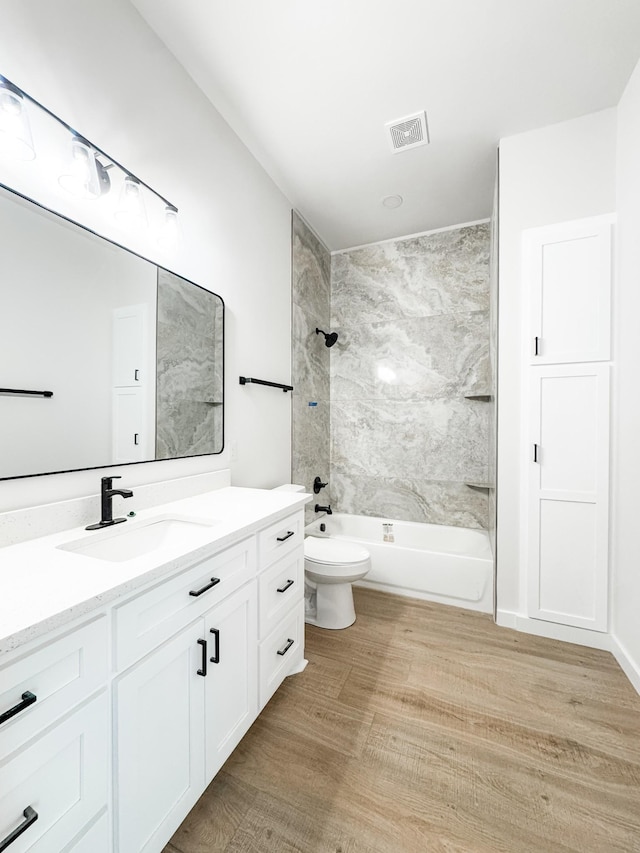 bathroom featuring bathtub / shower combination, visible vents, toilet, vanity, and wood finished floors