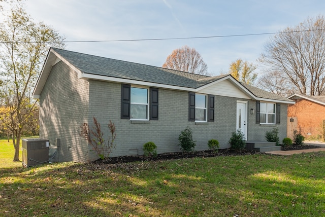 ranch-style house with a front yard and central air condition unit