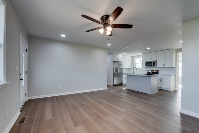 kitchen featuring white cabinetry, ceiling fan, a kitchen island, wood-type flooring, and stainless steel appliances