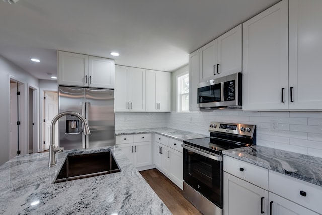 kitchen with light stone counters, sink, white cabinets, and appliances with stainless steel finishes