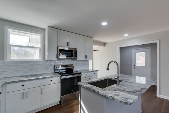 kitchen featuring white cabinets, sink, appliances with stainless steel finishes, and an island with sink