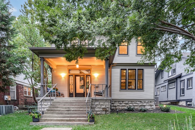 view of front of property featuring central AC, a front lawn, and covered porch