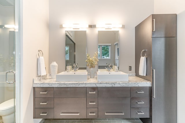 bathroom with an enclosed shower, vanity, and toilet