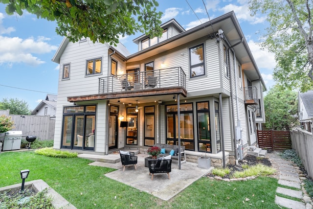 back of property with a yard, an outdoor hangout area, a balcony, and a patio area