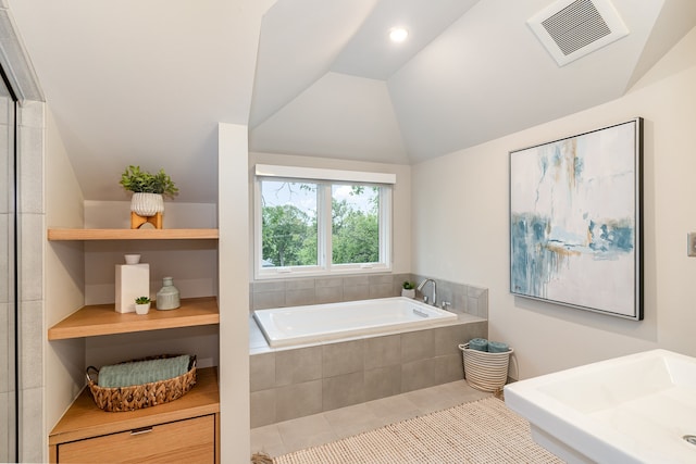 bathroom featuring tile patterned floors, tiled bath, sink, and vaulted ceiling