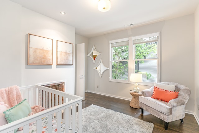 bedroom with dark hardwood / wood-style floors and a nursery area