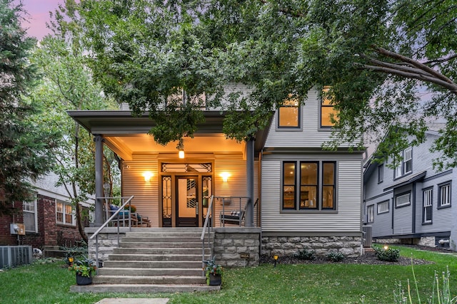 view of front of house featuring a porch, a yard, and cooling unit