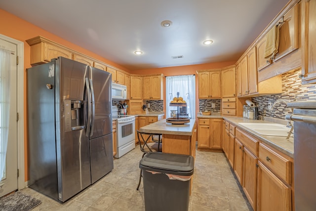 kitchen with light brown cabinets, white appliances, backsplash, sink, and a kitchen island