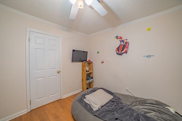 bedroom with ceiling fan, ornamental molding, a textured ceiling, and light wood-type flooring