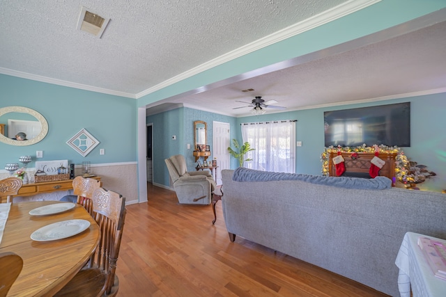 living room featuring ceiling fan, hardwood / wood-style floors, crown molding, and a textured ceiling