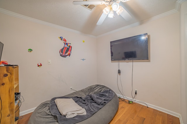 bedroom featuring hardwood / wood-style flooring, ceiling fan, ornamental molding, and a textured ceiling