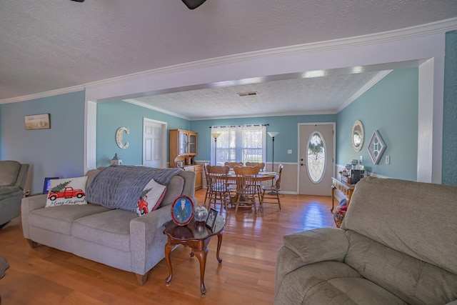 living room with ornamental molding, a textured ceiling, and light hardwood / wood-style flooring