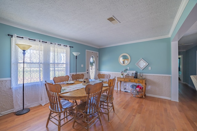 dining room featuring hardwood / wood-style flooring, ornamental molding, and a textured ceiling